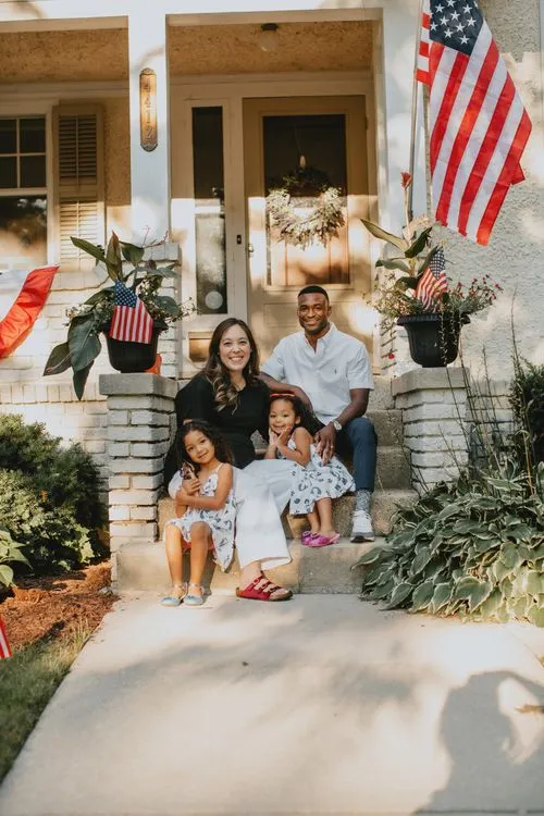 A family sitting on the front steps of a house.